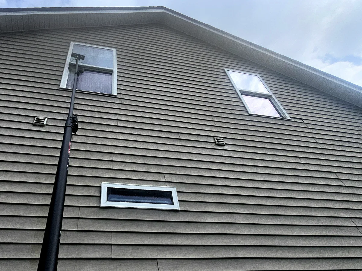 Glass Masters crew cleaning second-story windows with professional reach equipment